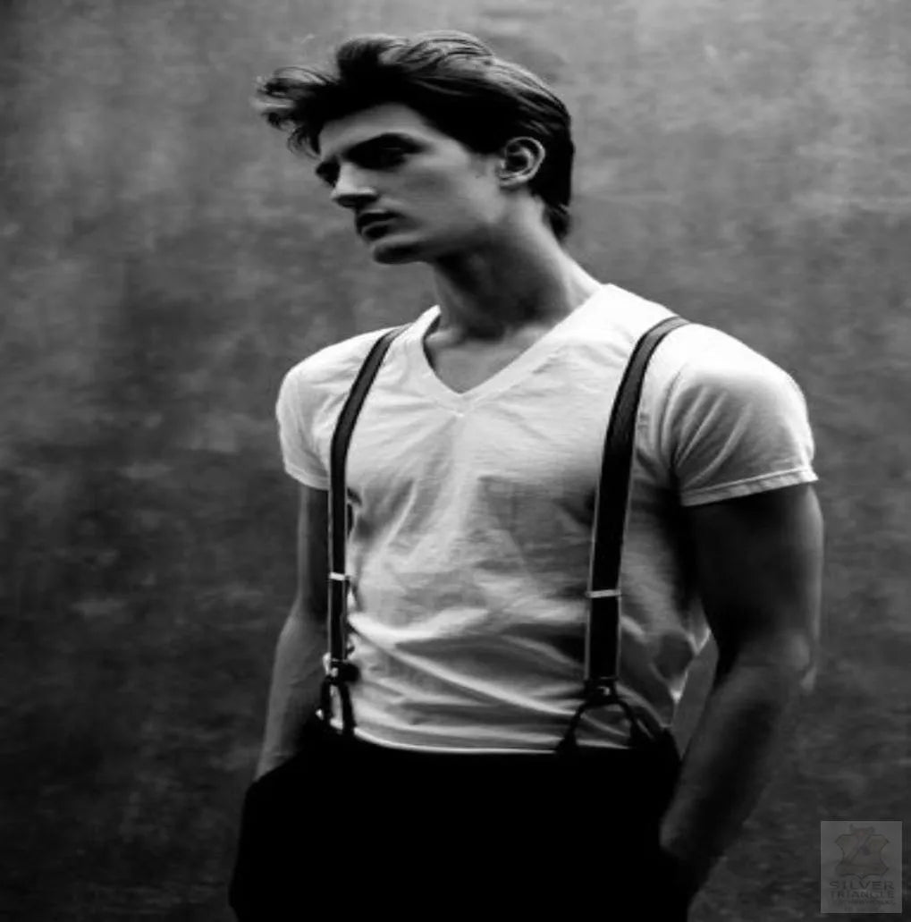 A man in a whit shirt wearing a pair of suspenders.